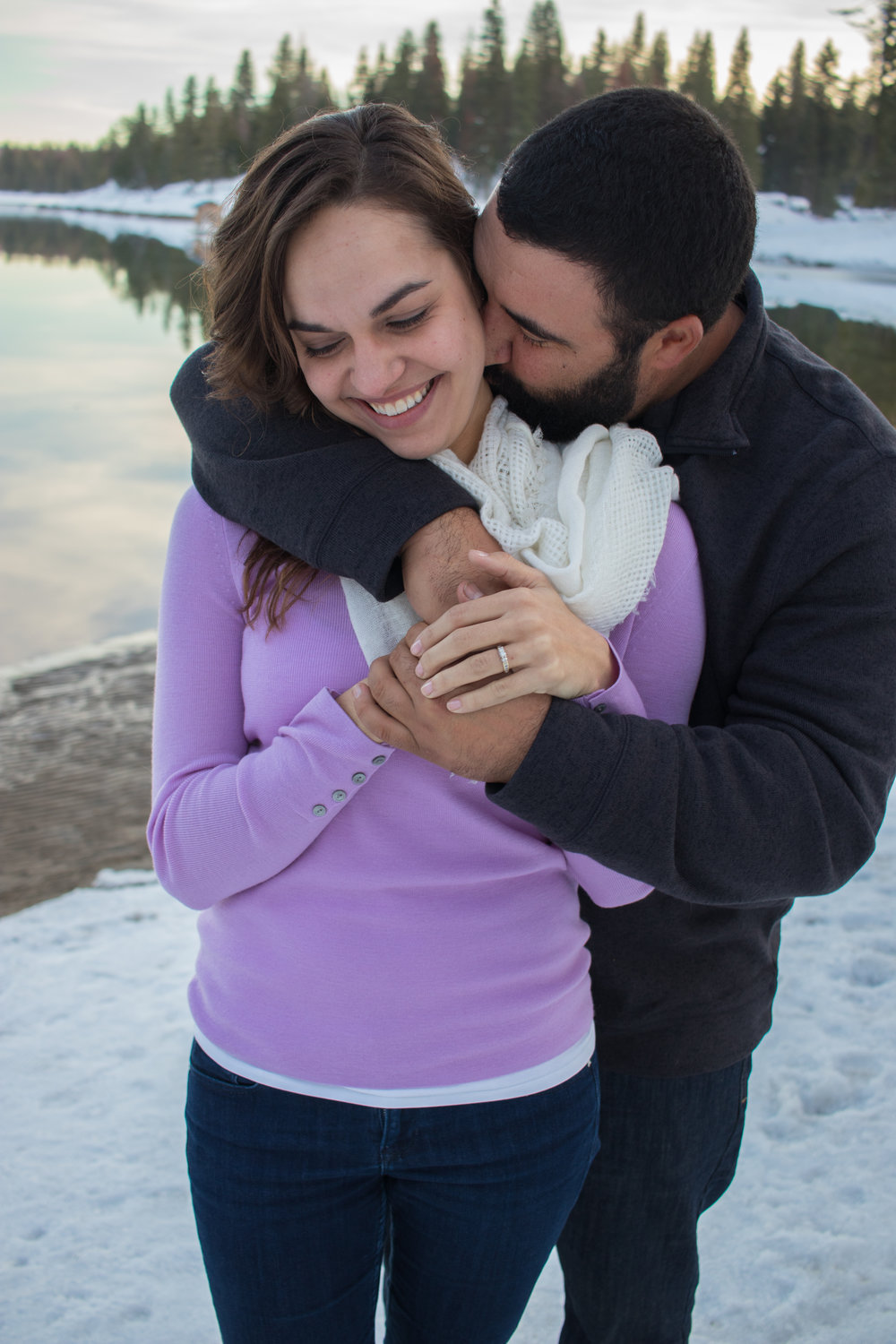 couple hugging and kissing by the shores of shaver lake in the snow
