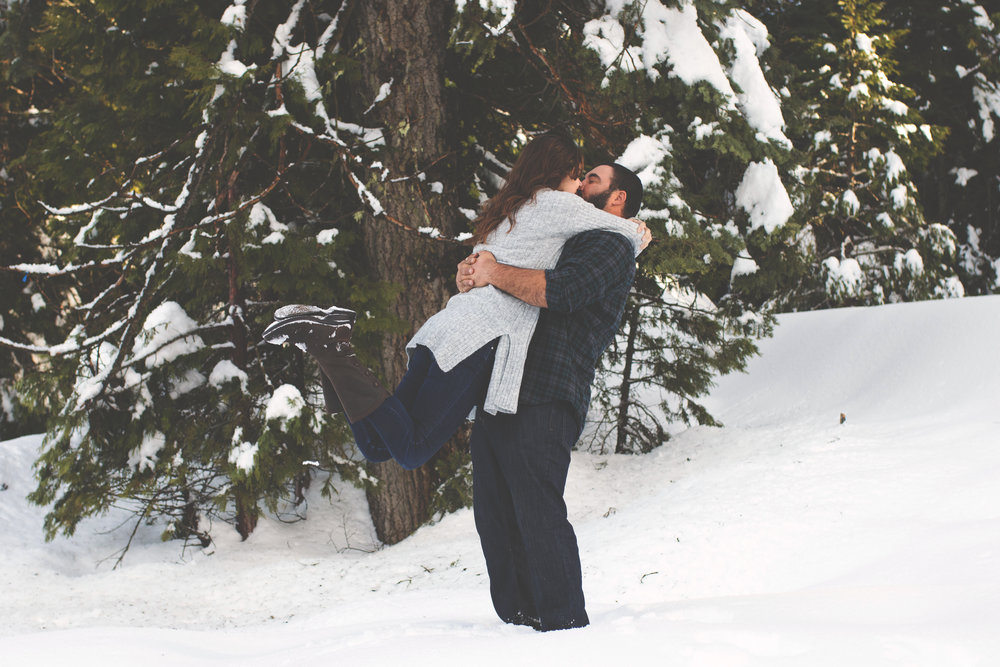 engaged couple kissing in the snow