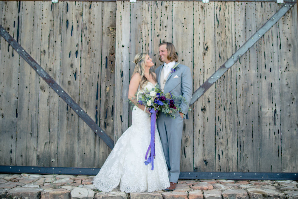 bride and groom standing in front of barn doors at oak heart estate in paso robles ca