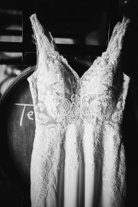 premier bride's perfect dress hanging in the barrel room at kings river winery in sanger