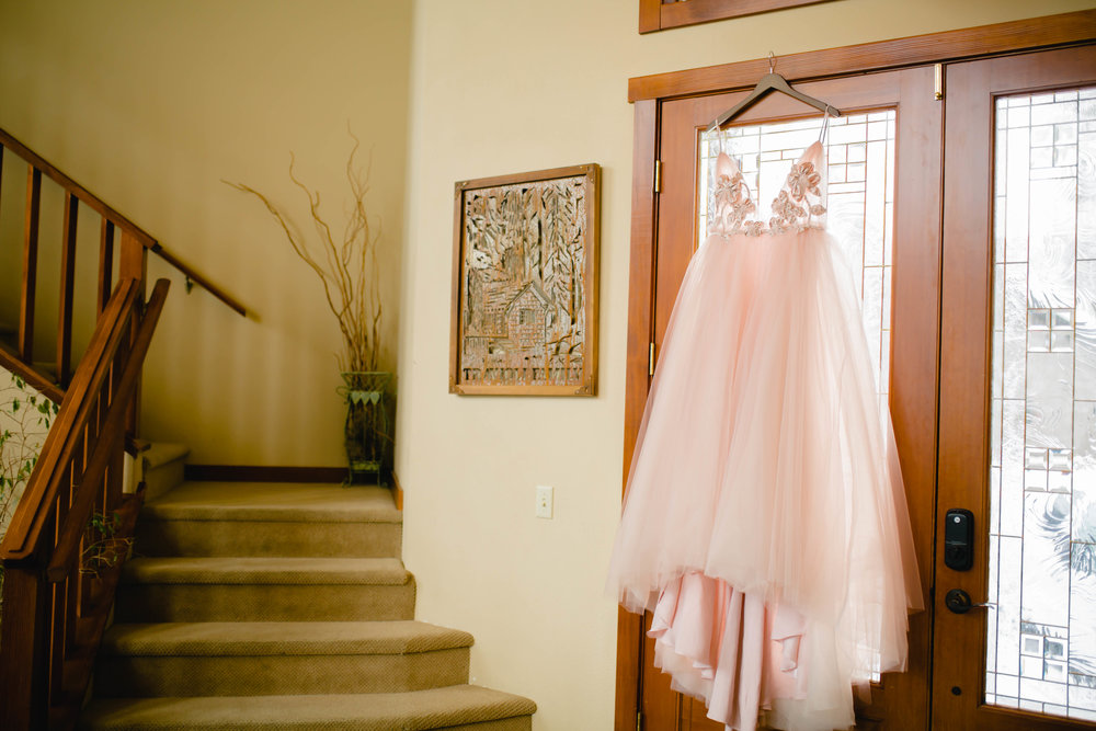 blush wedding dress hanging in front of the front door