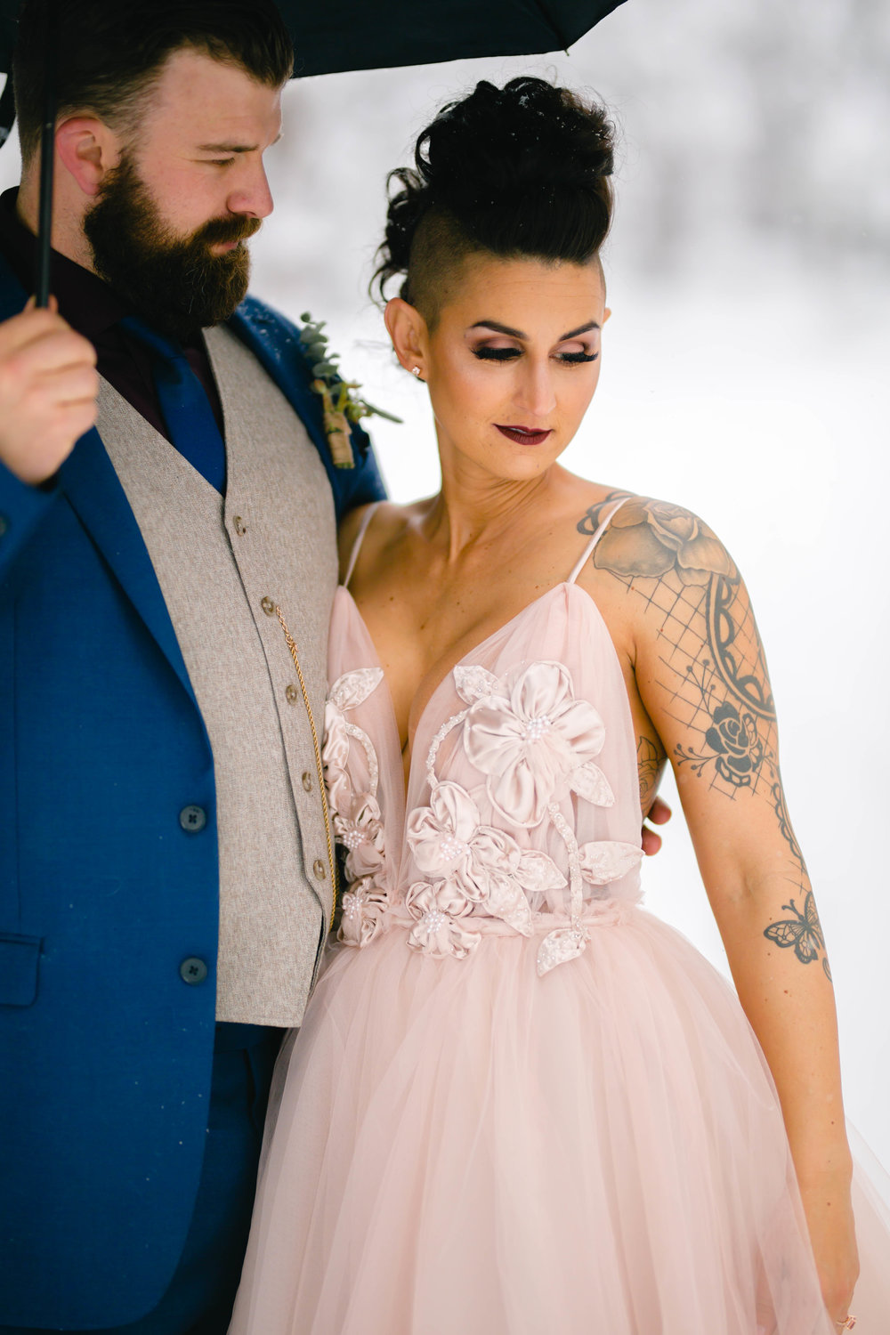 intimate wedding photo of a bride in a blush wedding gown and a groom in a blue suit