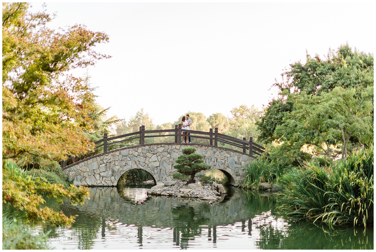 newly engaged couple embracing on the bridge at Shinzen Japanese Gardens in Woodward Park in Fresno