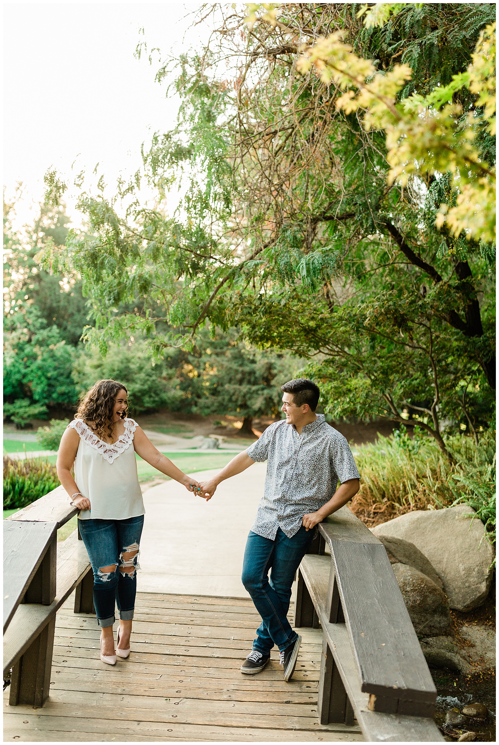 couple holding hands on a bridge during a summer engagement photo shoot in fresno 
