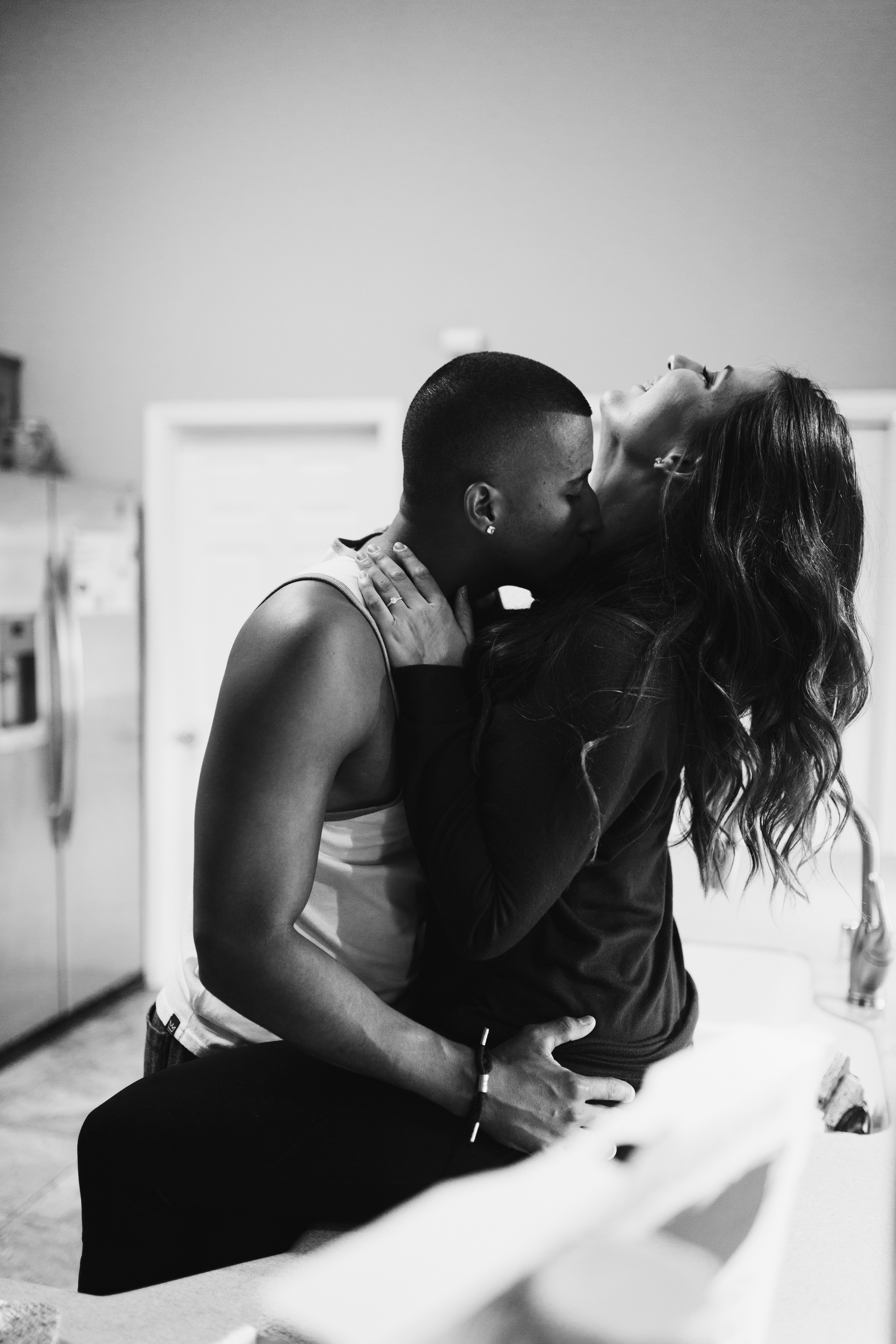 black and white image of a couple kissing on the kitchen counter