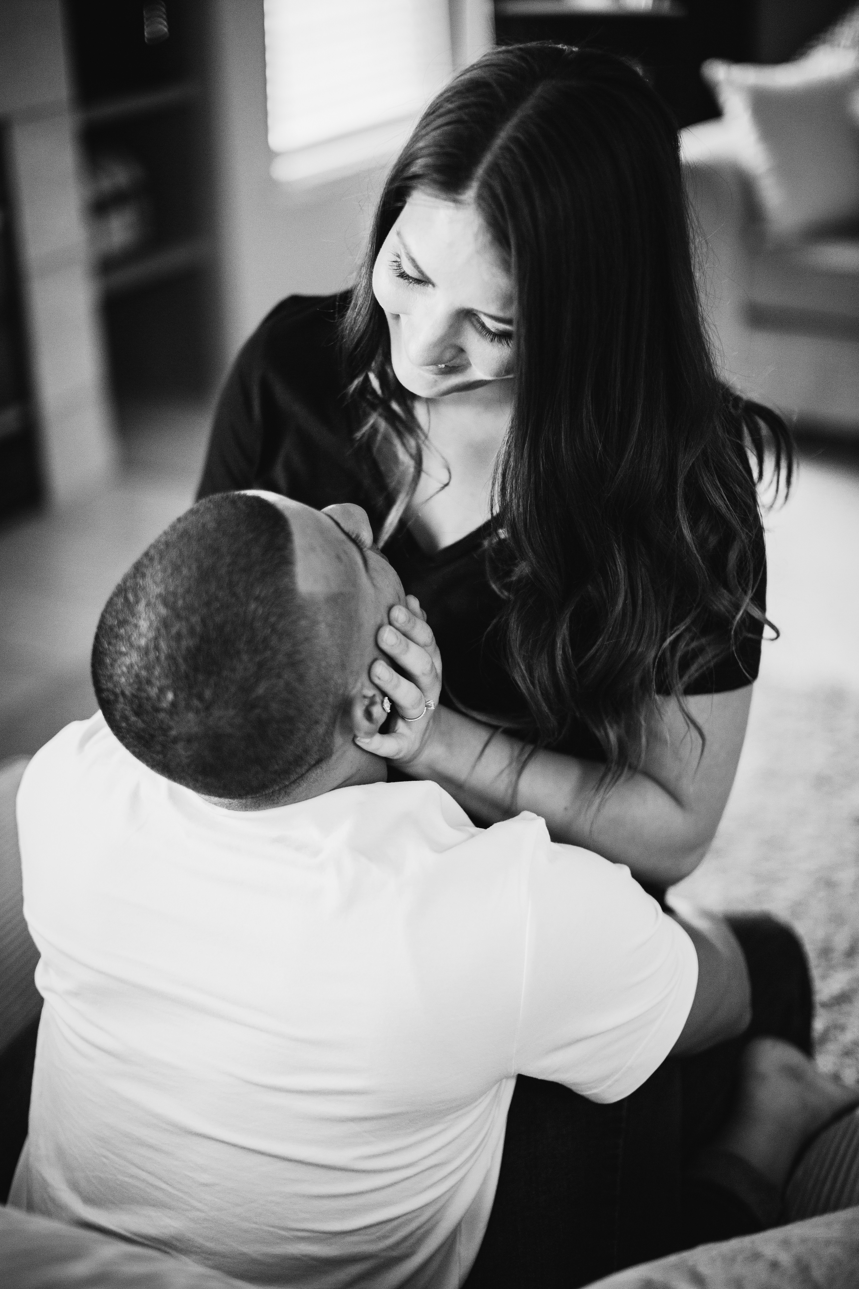 newly engaged couple embracing on the couch for an in home engagement photo shoot