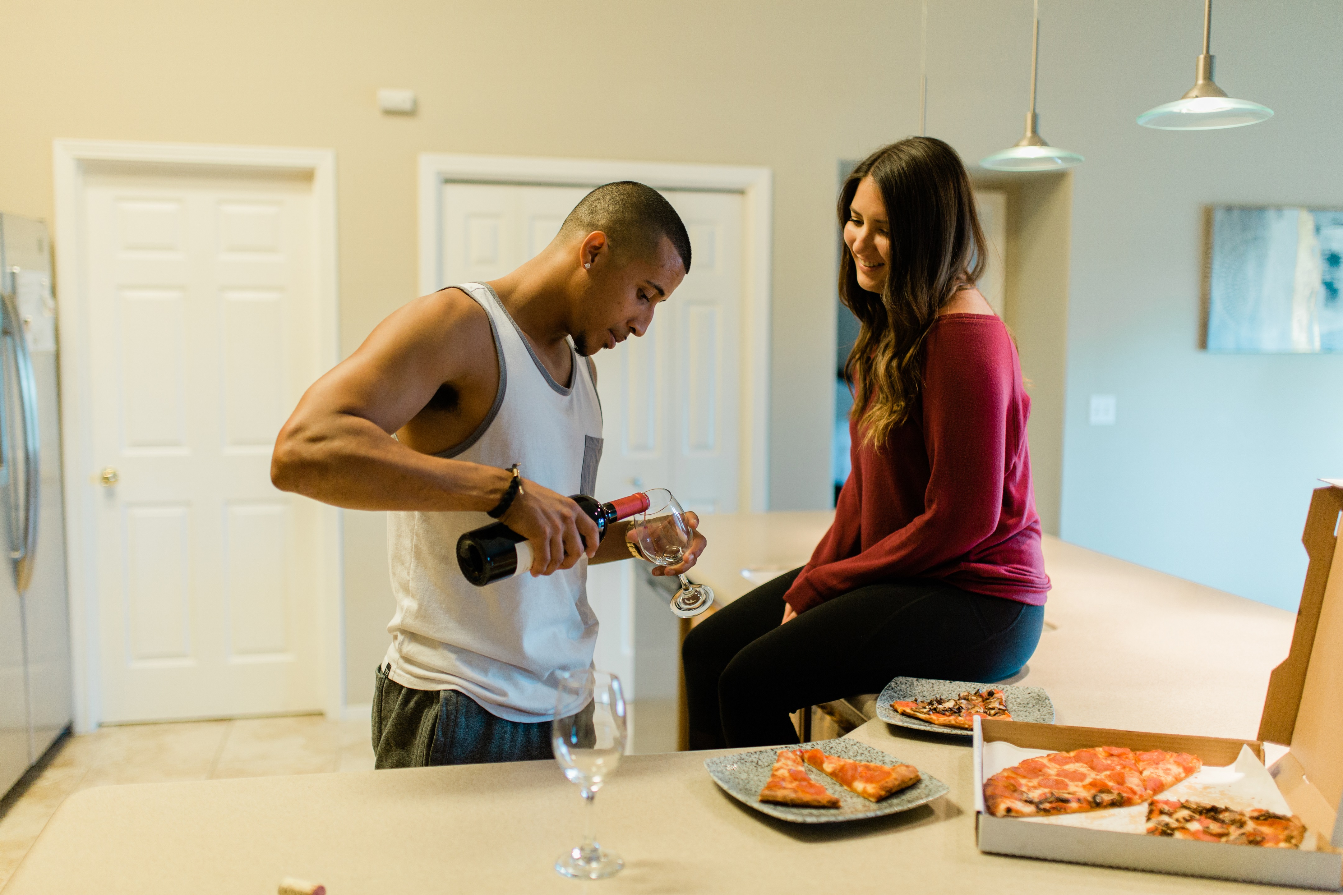 newly engaged couple pouring wine and eating pizza