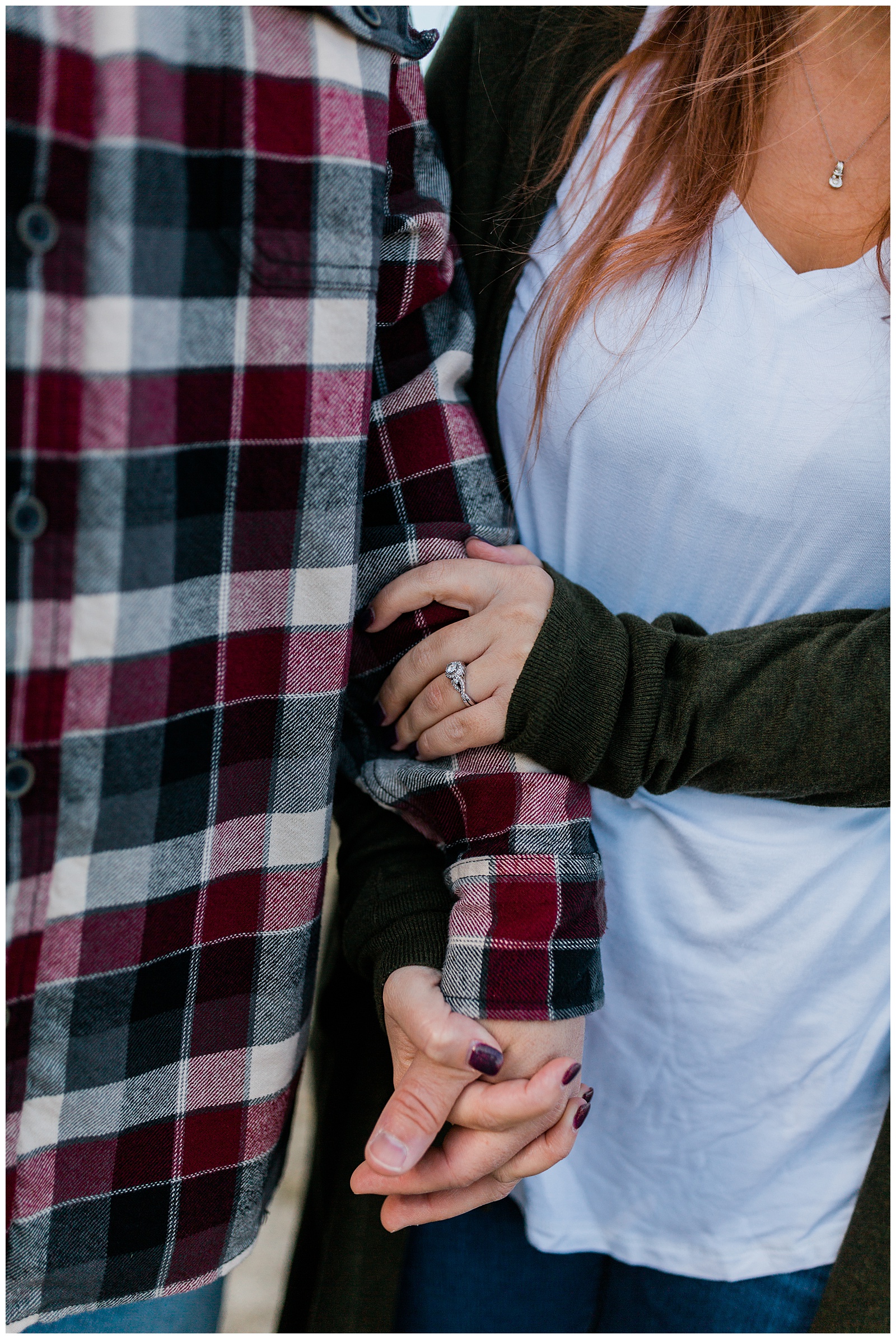 newly engaged couple holding hands and showing off the engagement ring