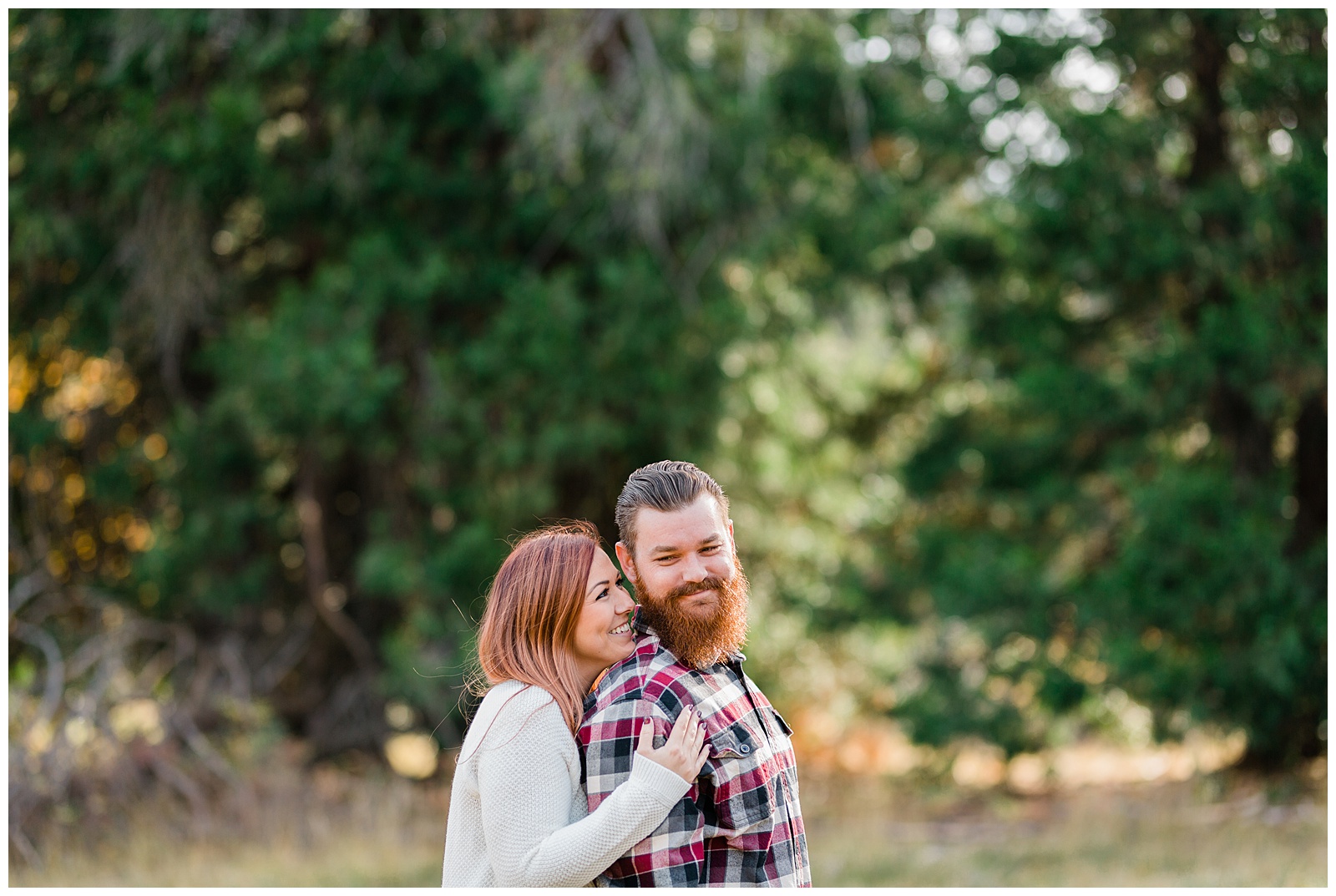 engaged couple embracing in a meadow for a fall engagement photo shoot