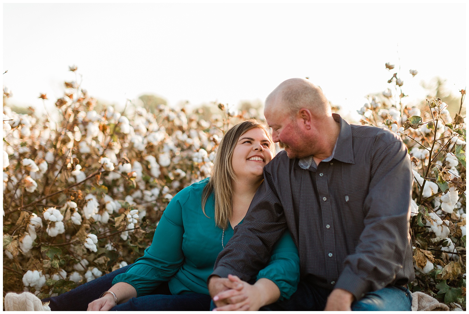 newly engaged couple sitting in a cotton field