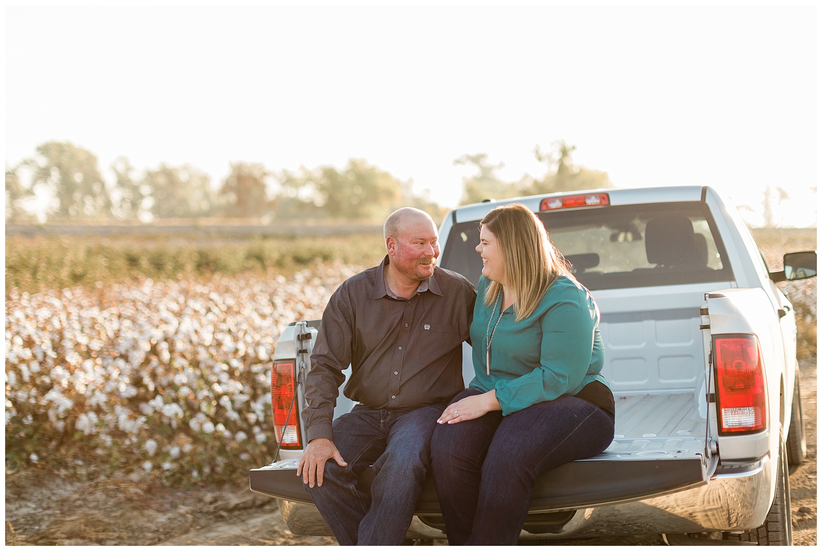 couple sitting on a tailgate in a cotton field