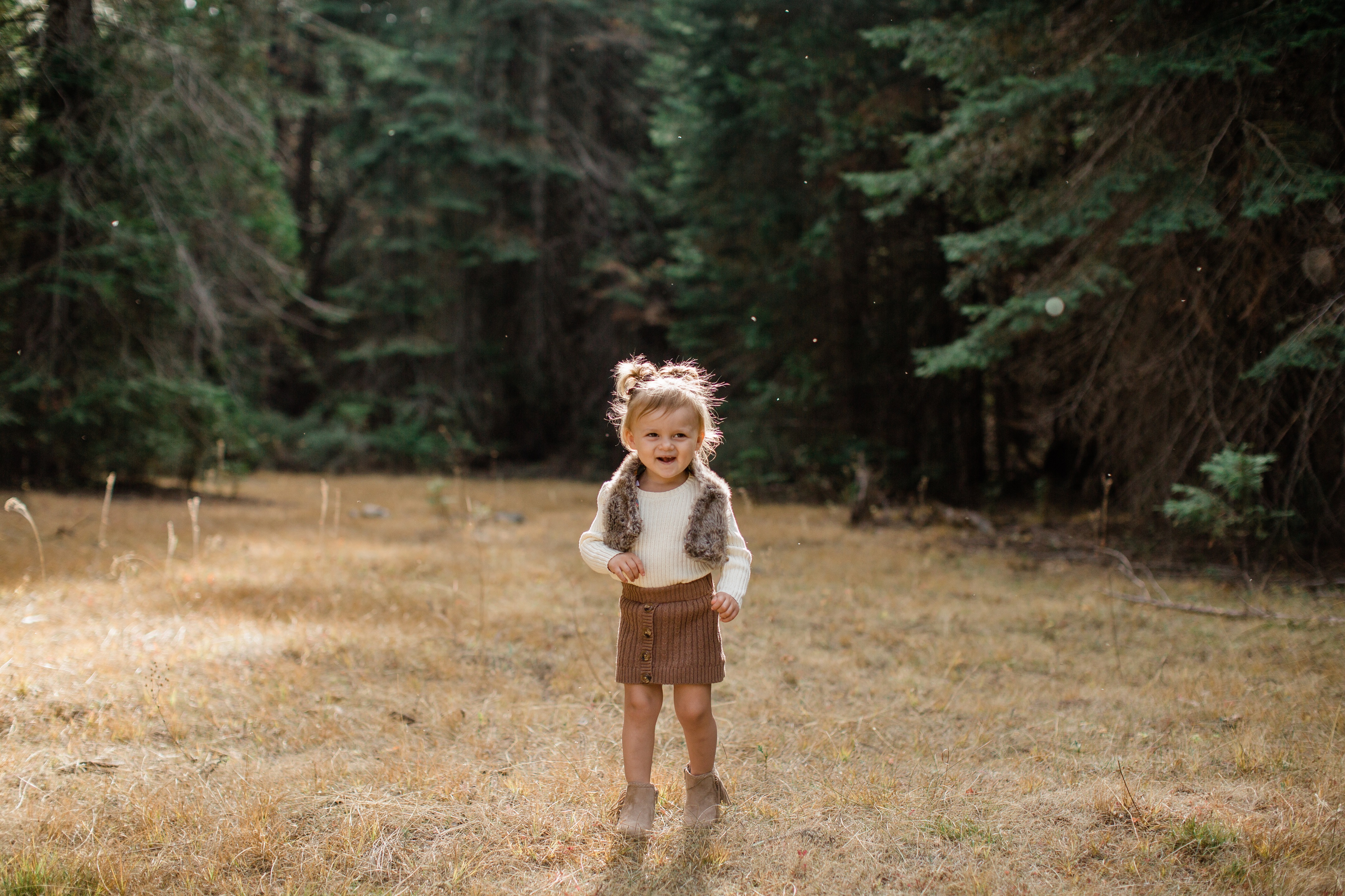 little girl walking through a meadow in the fall smiling