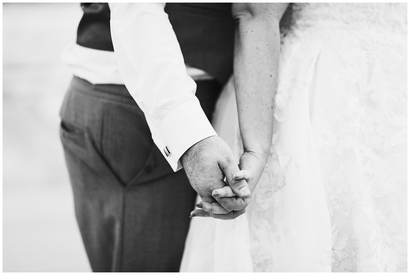 black and white photo of a bride and groom holding hands