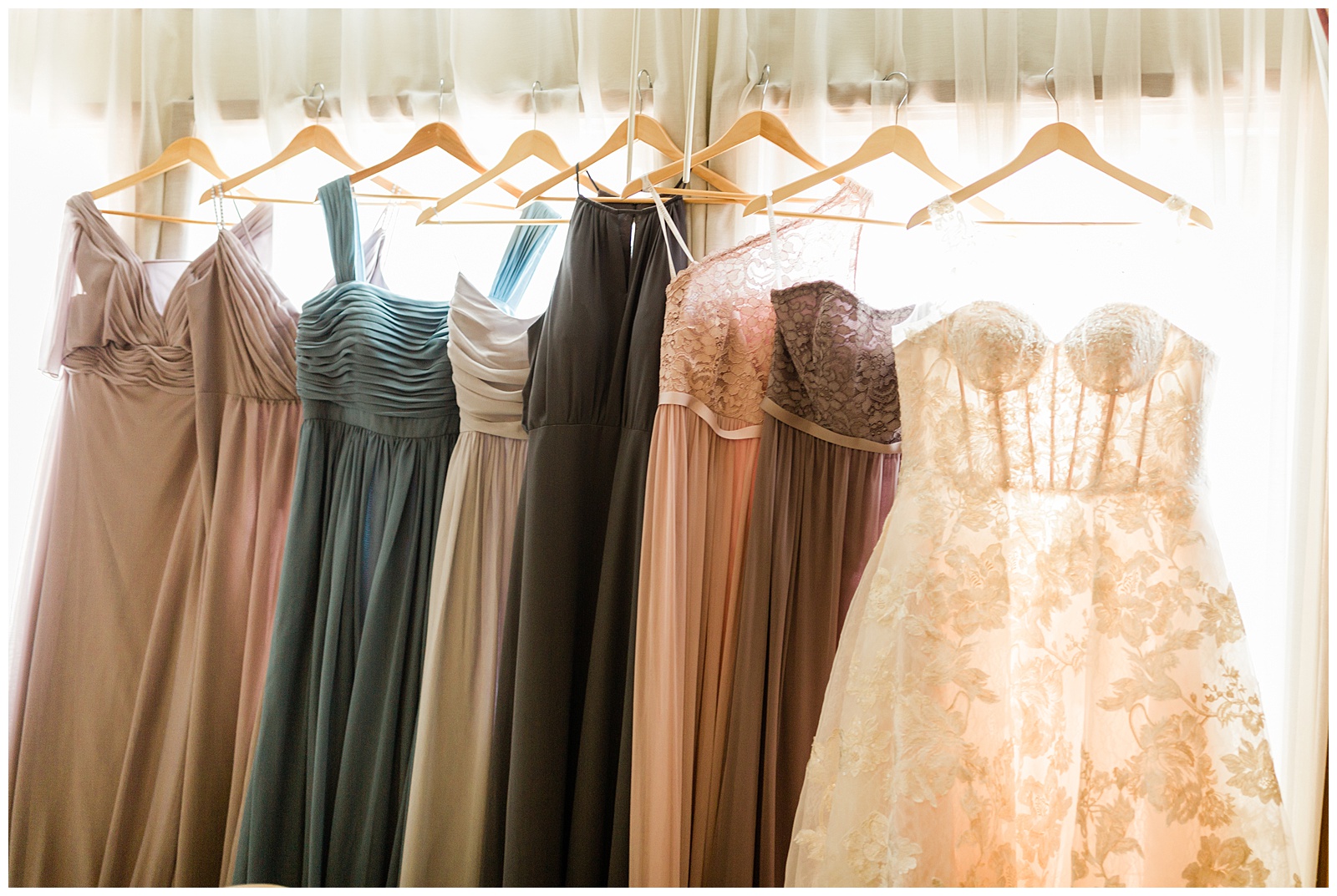 bridesmaid dresses and wedding dress hanging in front of a window