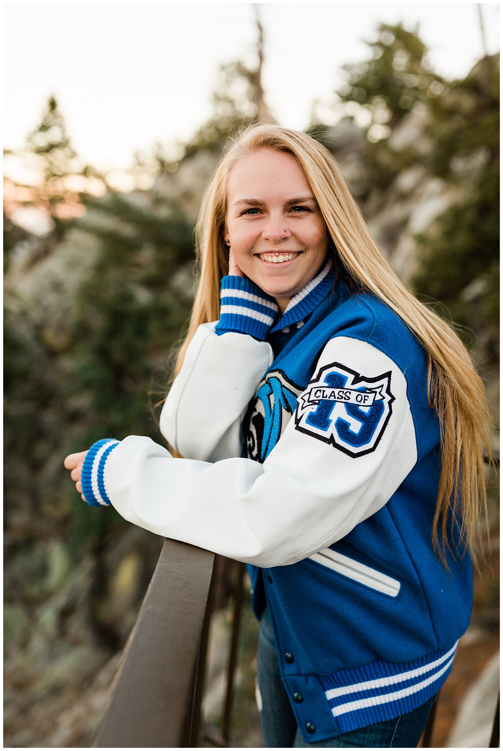 senior portraits in the mountains in the fall with blue and white high school letterman jacket