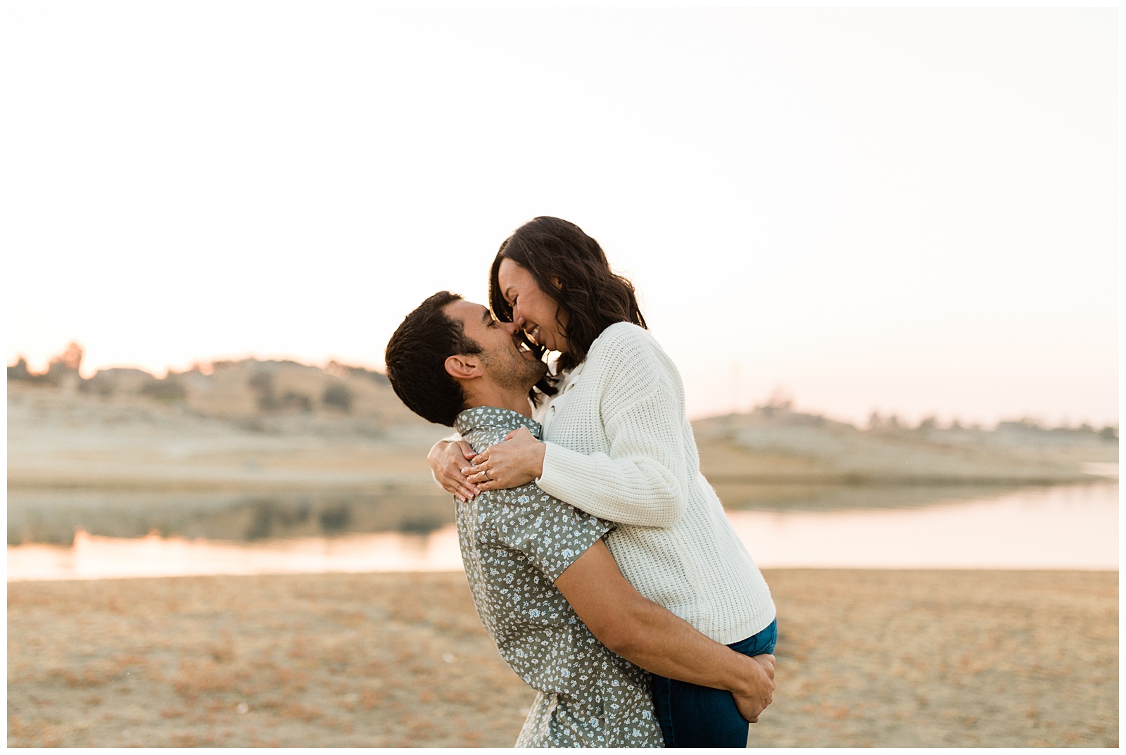 couple kissing by the lake at sunset during an engagement shoot at millerton lake