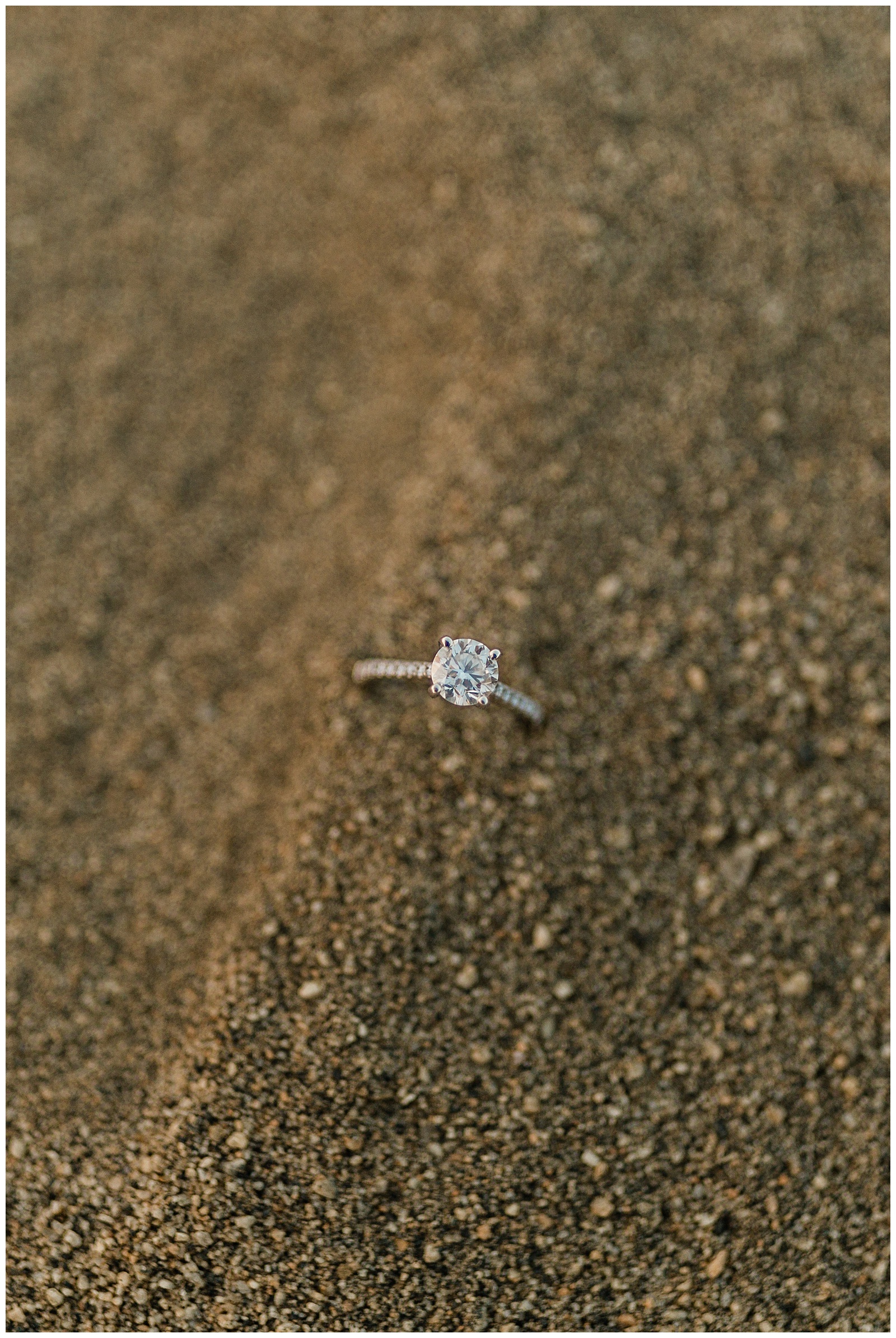 close up shot of an engagement ring in the sand