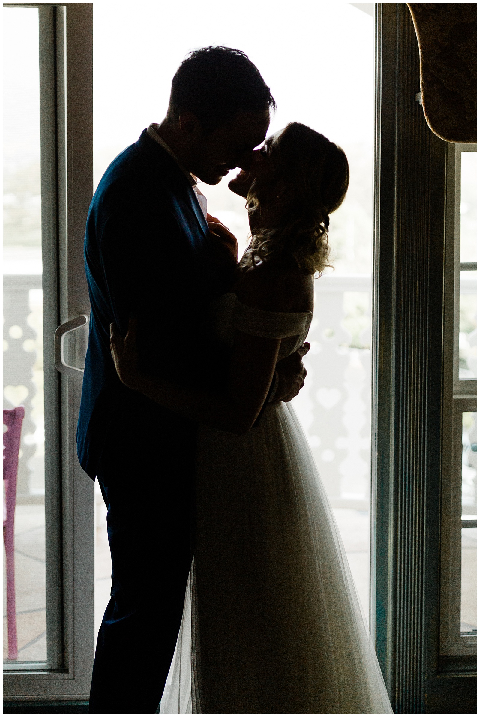 Silhouette shot of the bride and groom in front of a window
