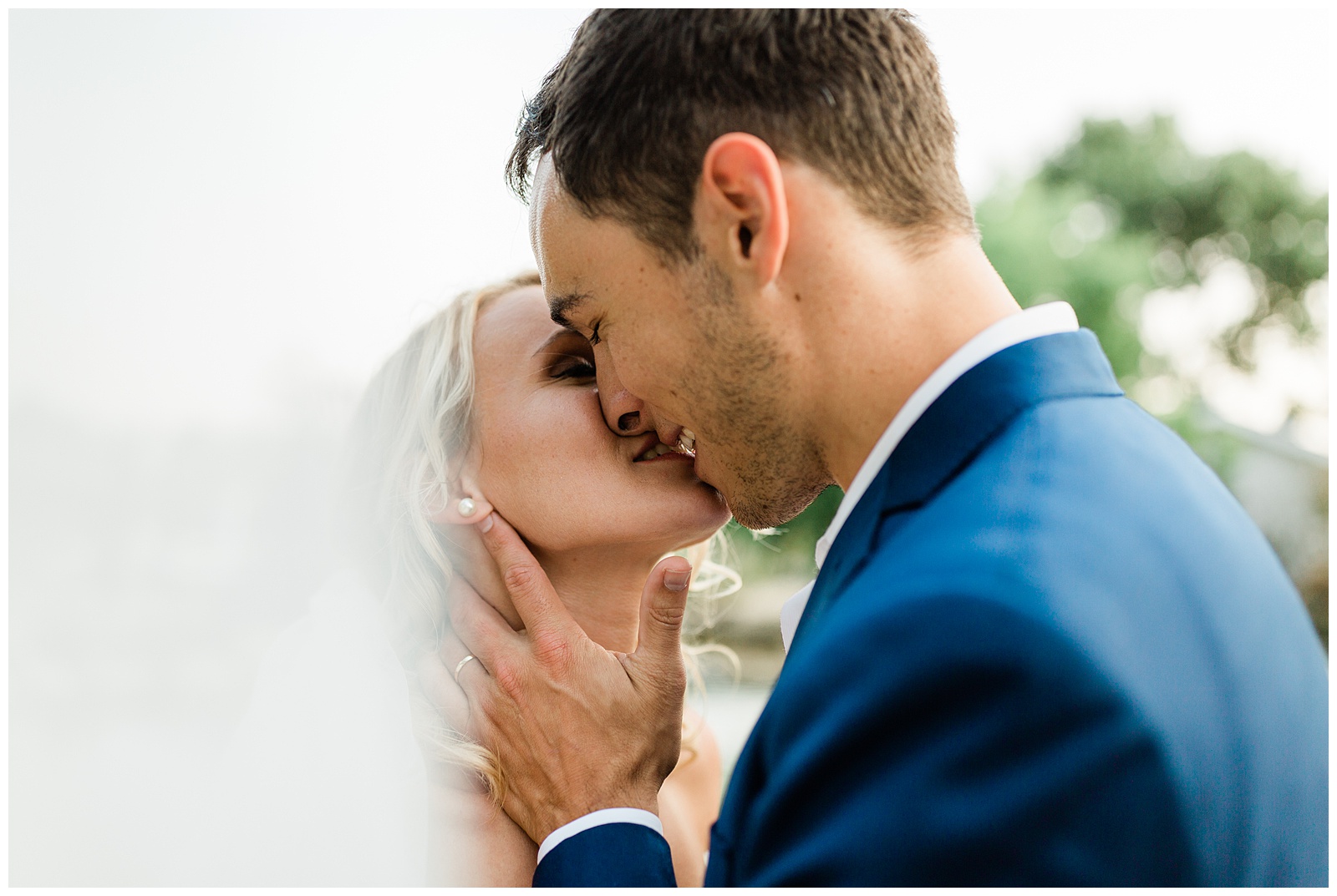 Bride and groom kissing behind the wedding veil