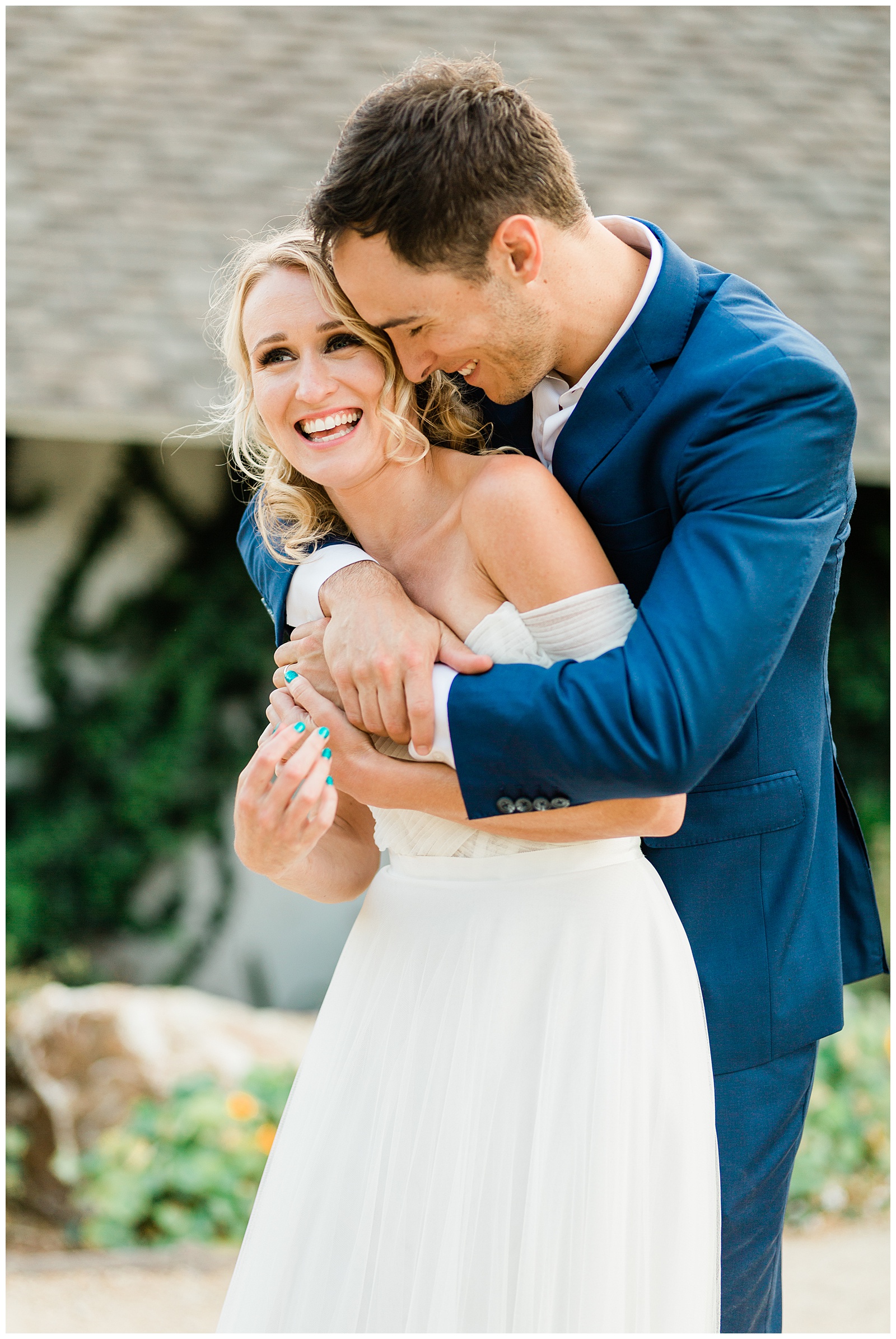 Candid wedding portrait of a newlywed couple hugging and laughing