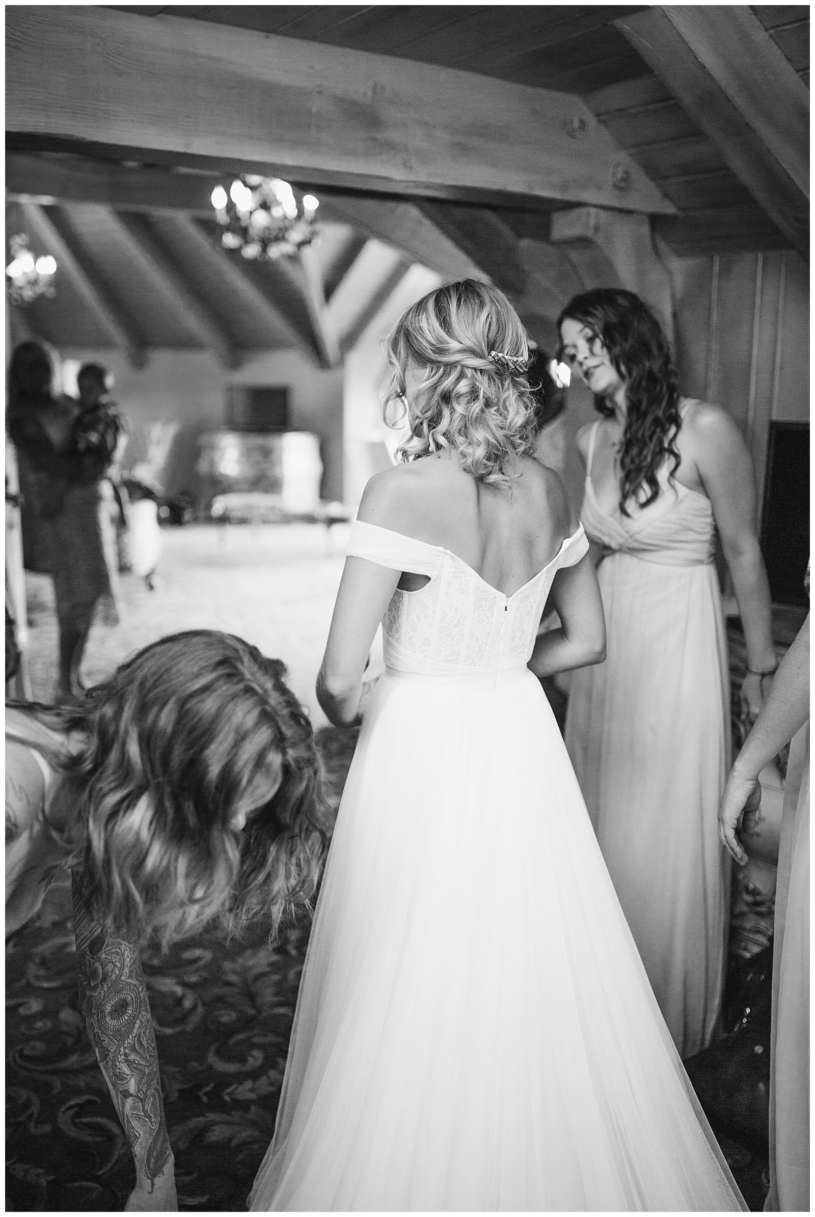 Bridesmaids helping the bride into her wedding gown
