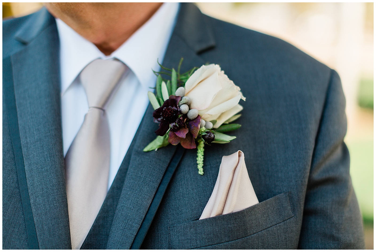 ivory rose boutonniere on a grey tuxedo