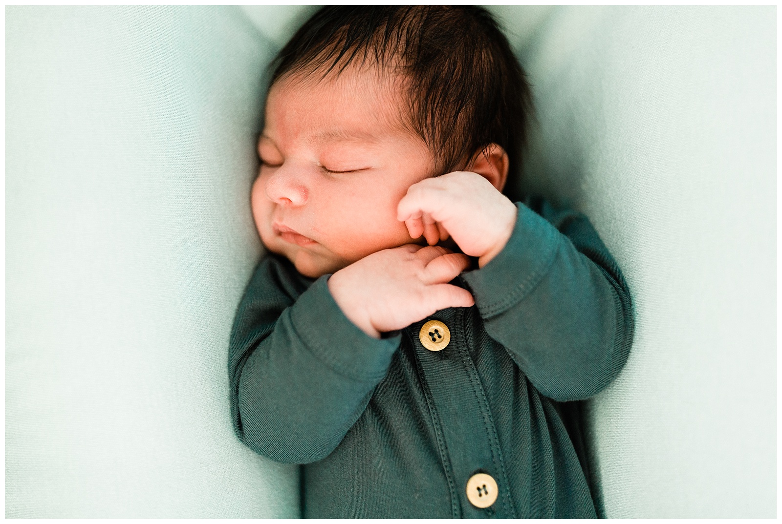 sleeping newborn baby boy in a blue onesie