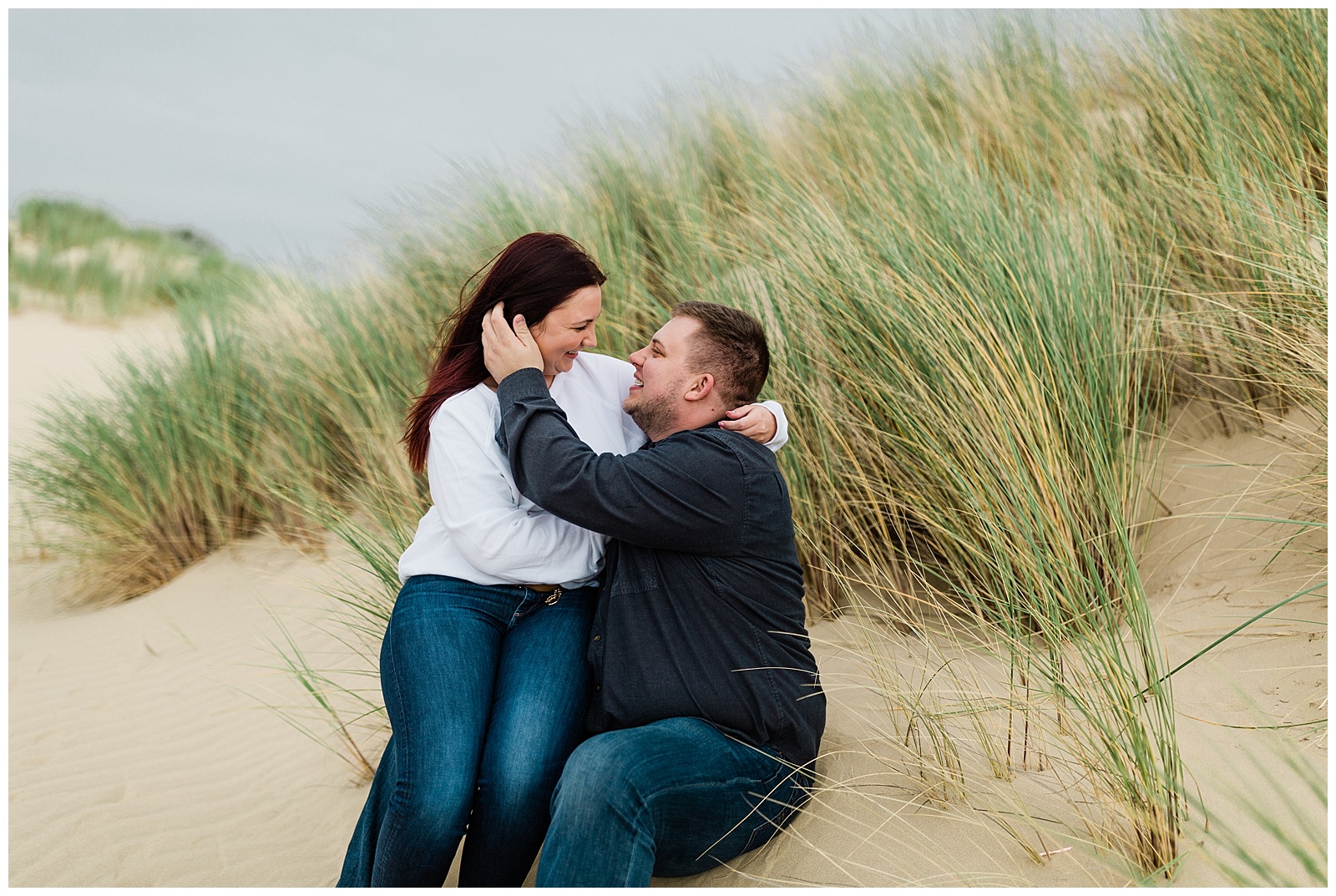 couple embracing in the windy grasses of the pismo beach sand dunes