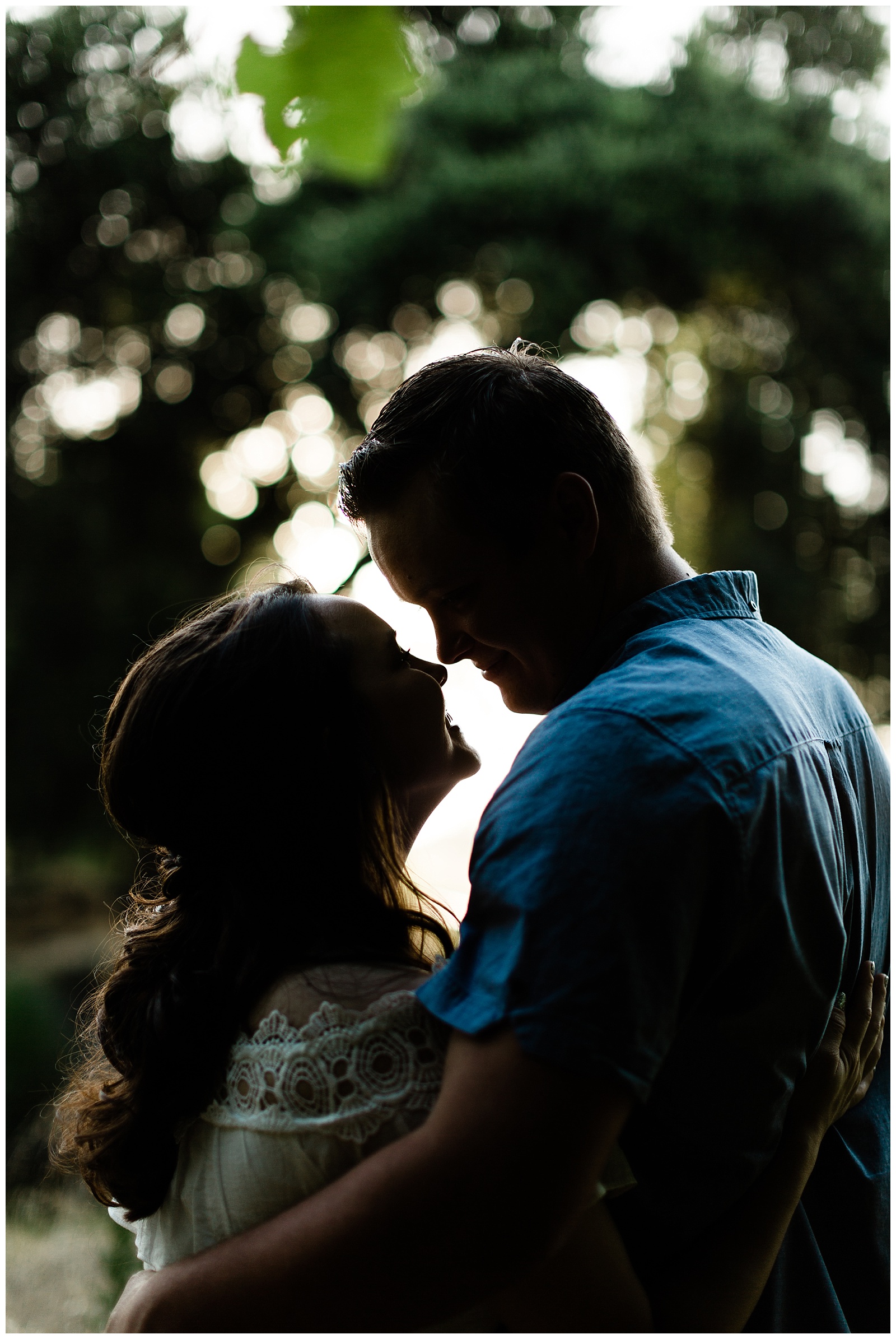 silhouette of a couple touching noses and smiling for engagement photos