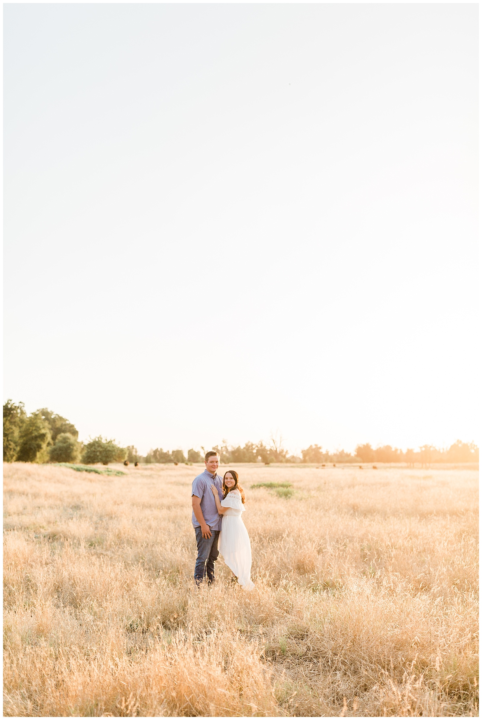 couple standing in the middle of an open field at sunset