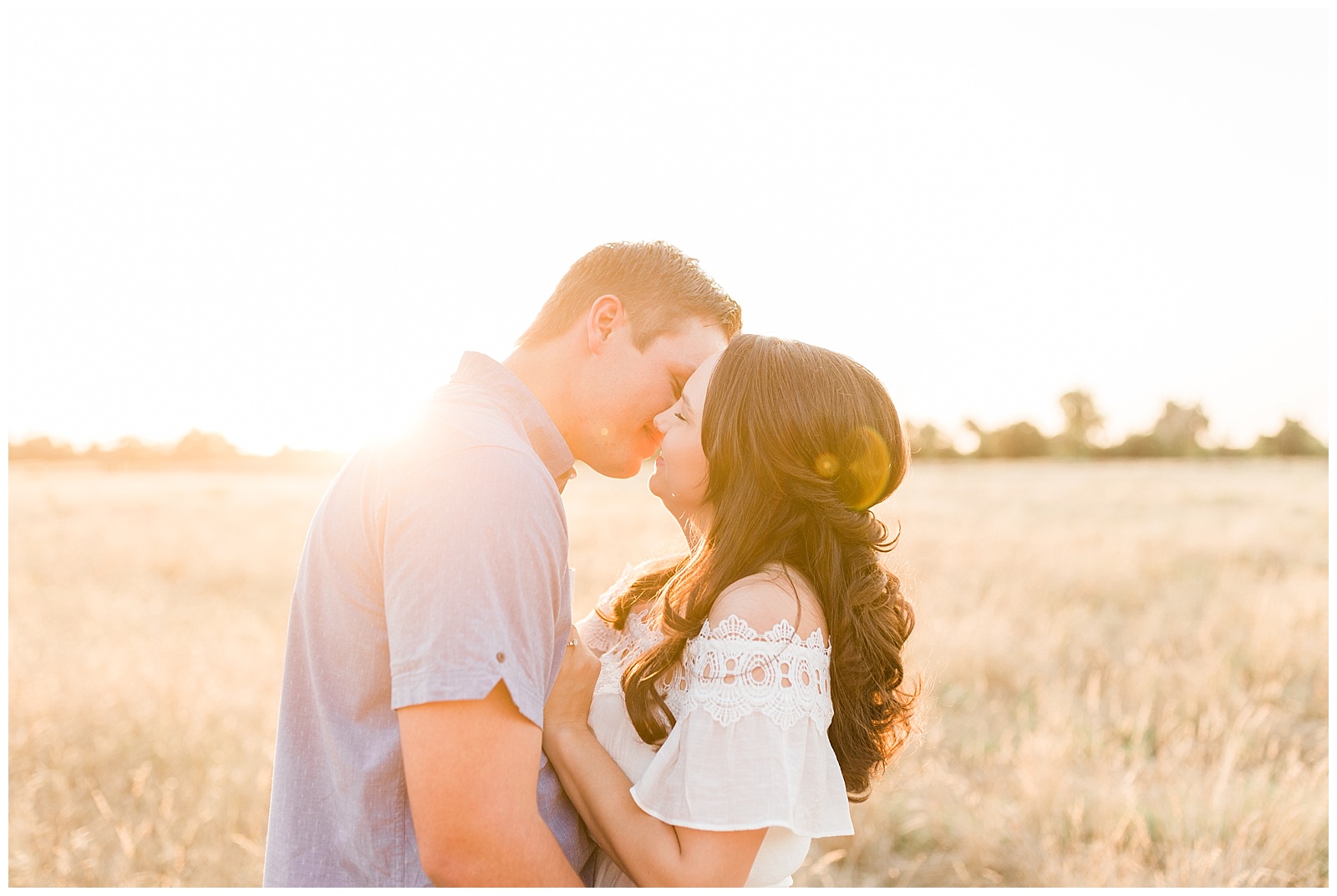 engaged country couple smiling and kissing at sunset
