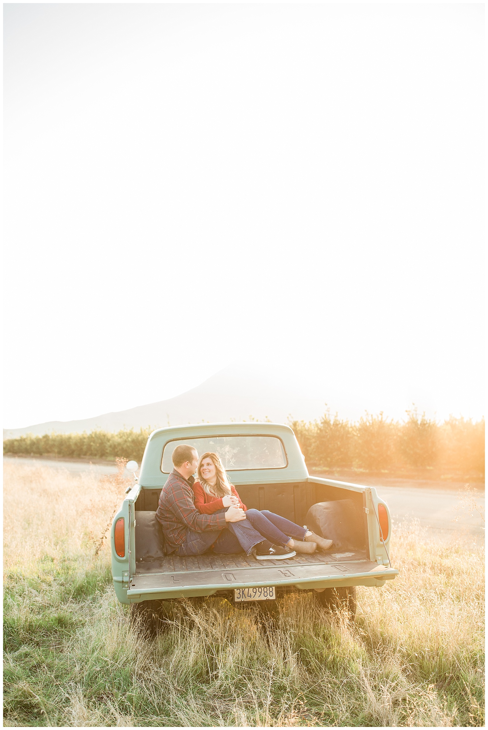 couple cuddling in the bed of an old ford pickup at sunset