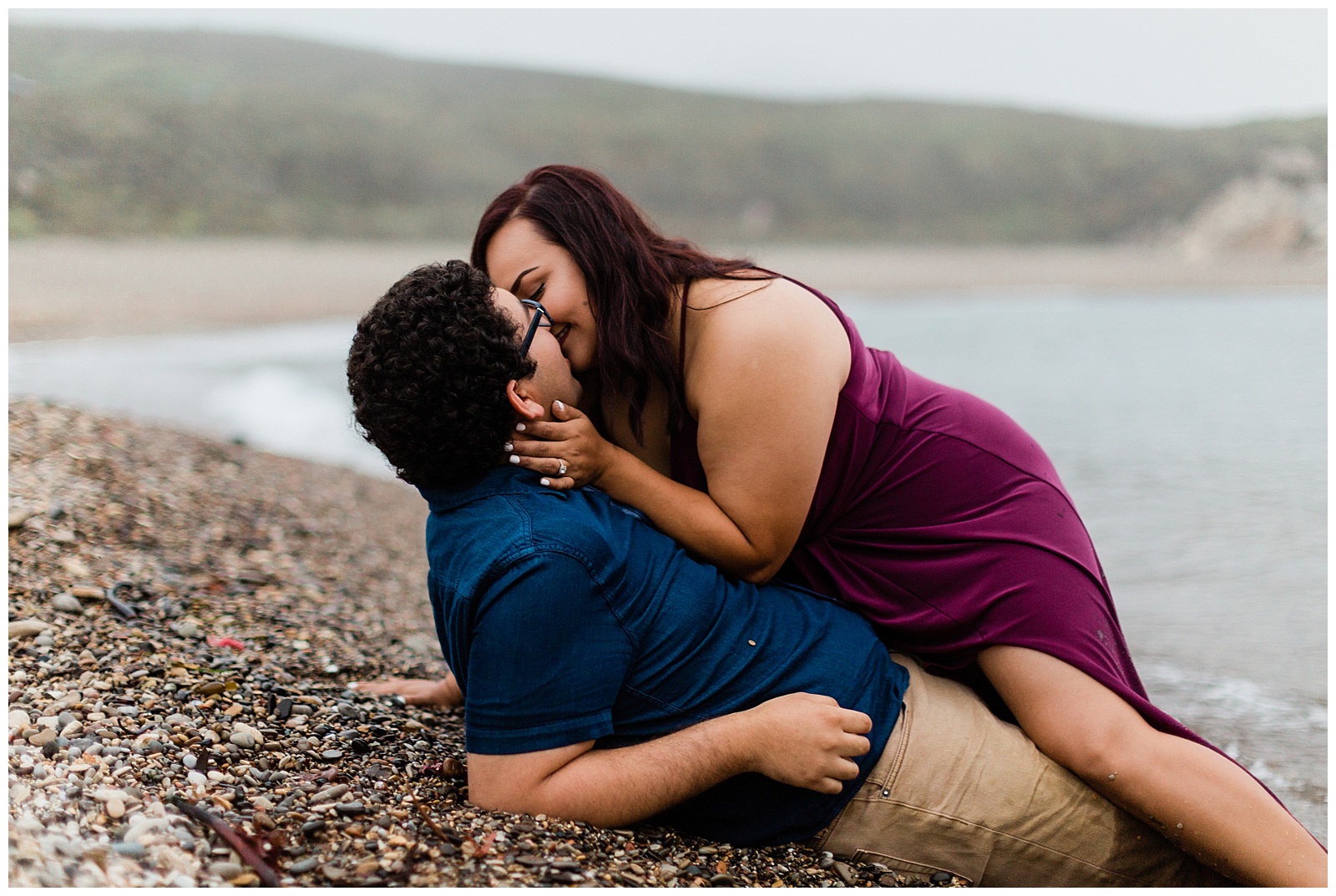 engaged couple lying on the beach and kissing in the fog