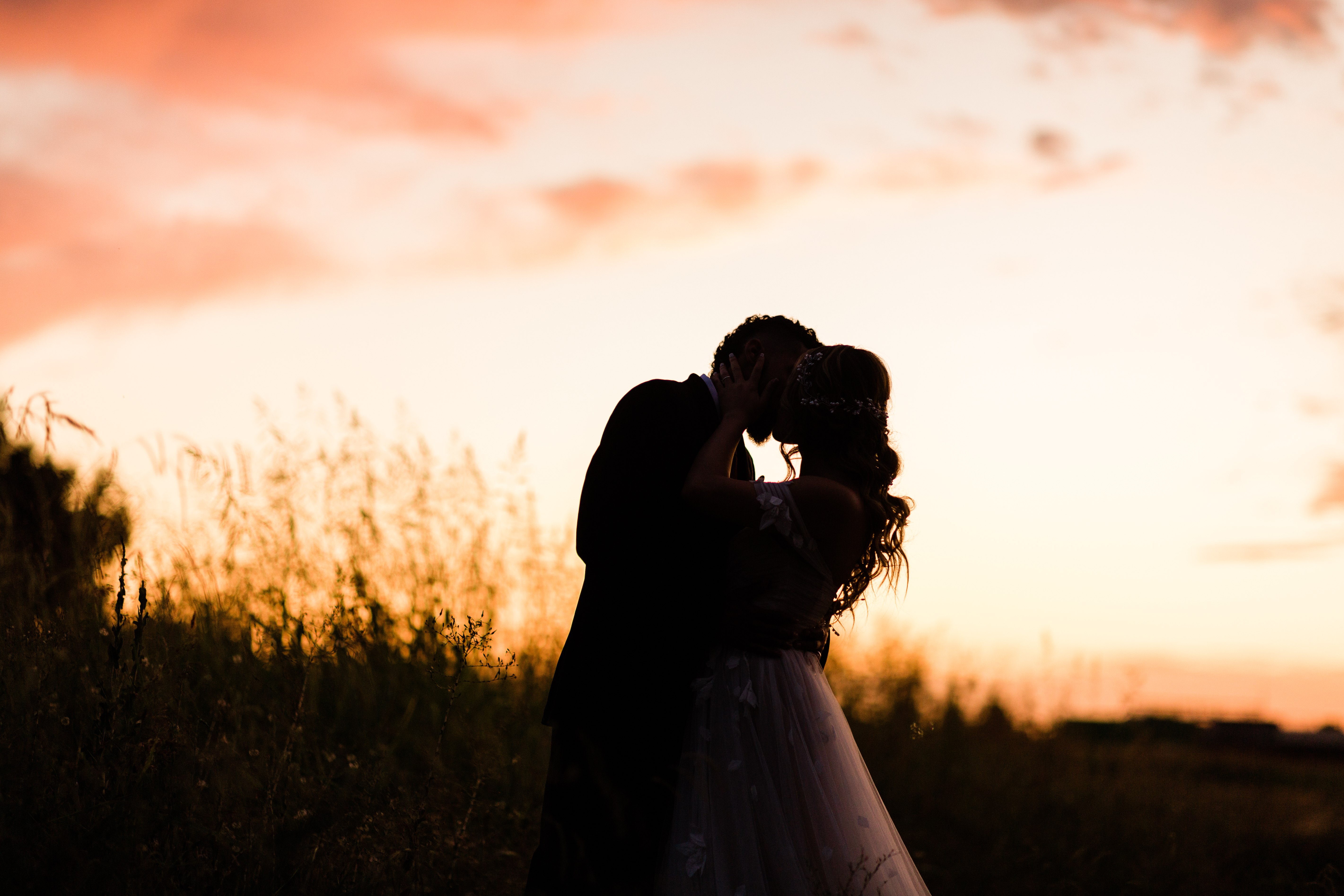 bride and groom kissing at sunset in a wheat field