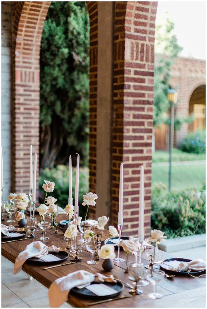 minimalistic wedding reception decor with black plates, blush linens and soft pastel florals