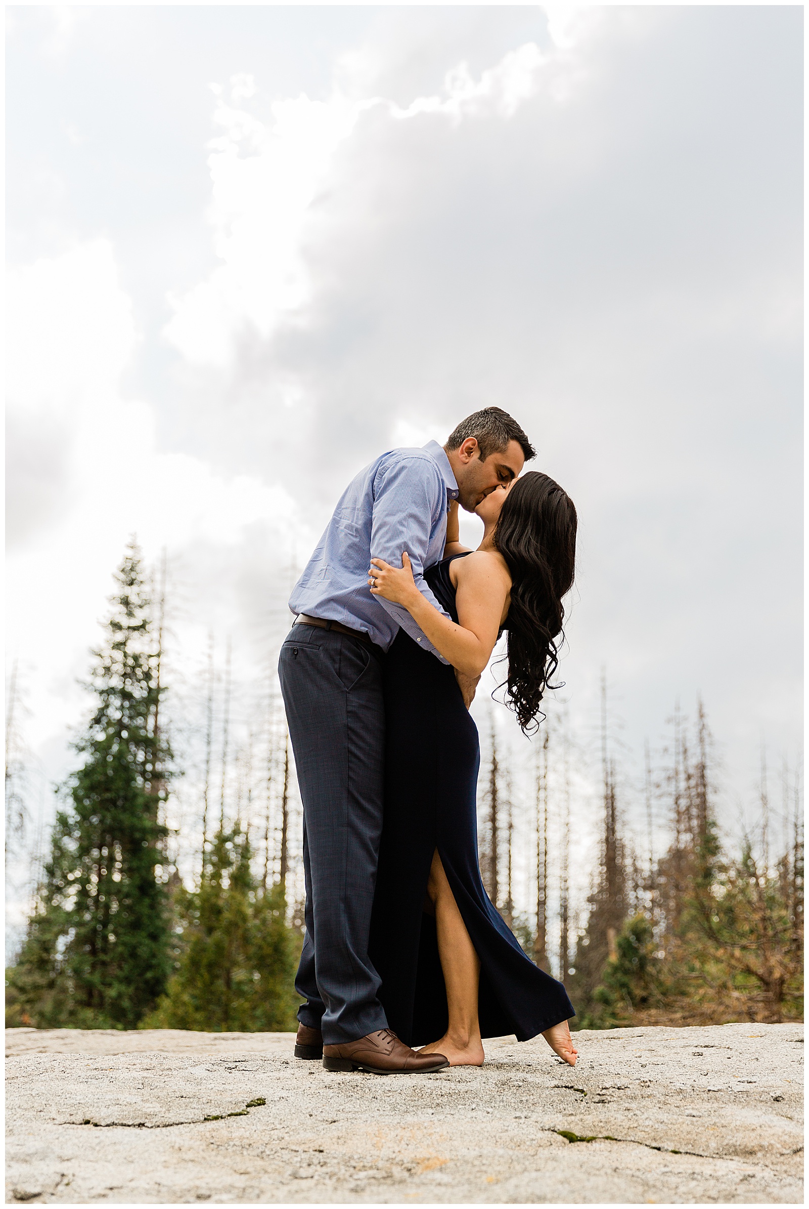 epic engagement photo on top of a rock in the mountains of a couple kissing