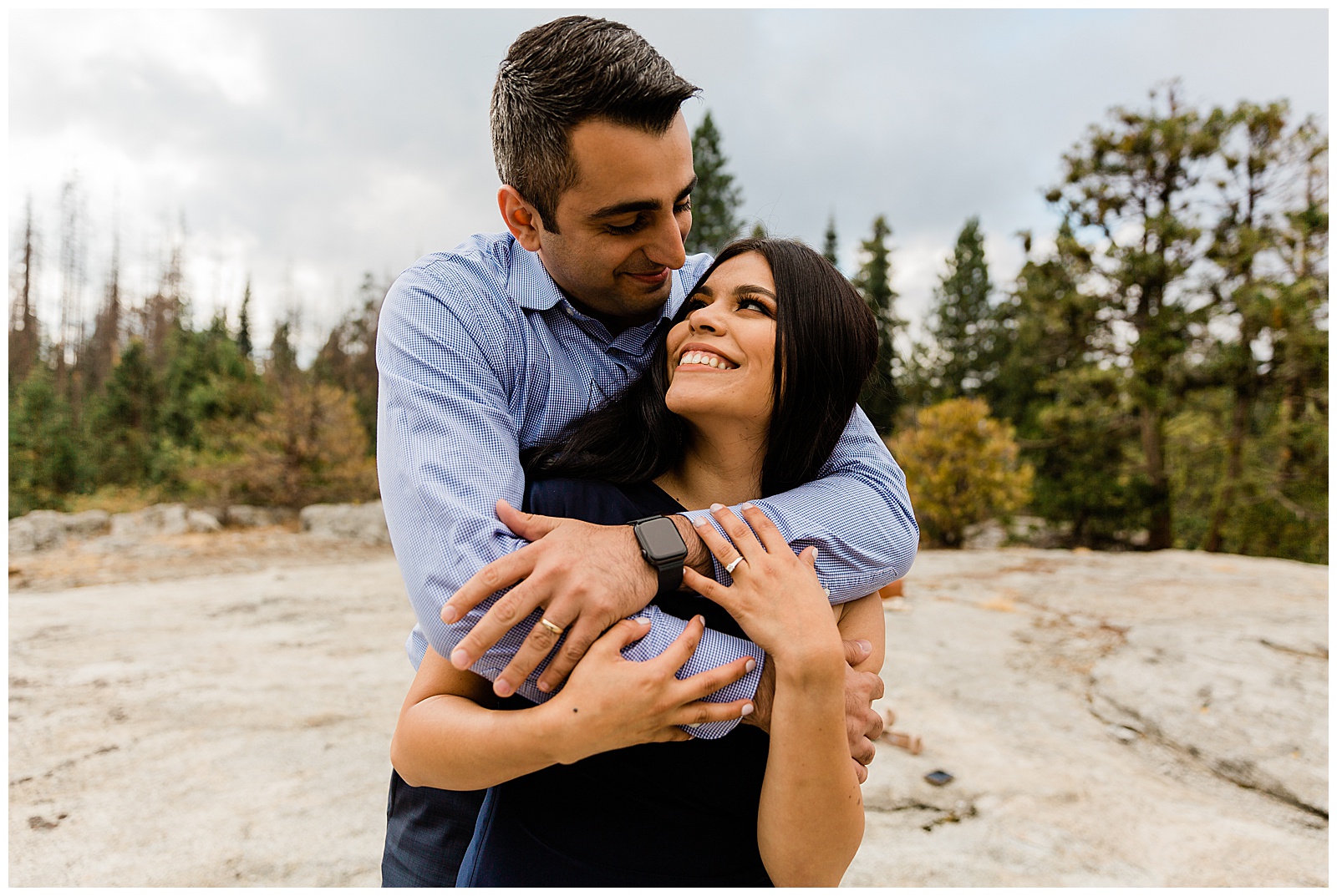 engaged couple hugging and smiling on a rock
