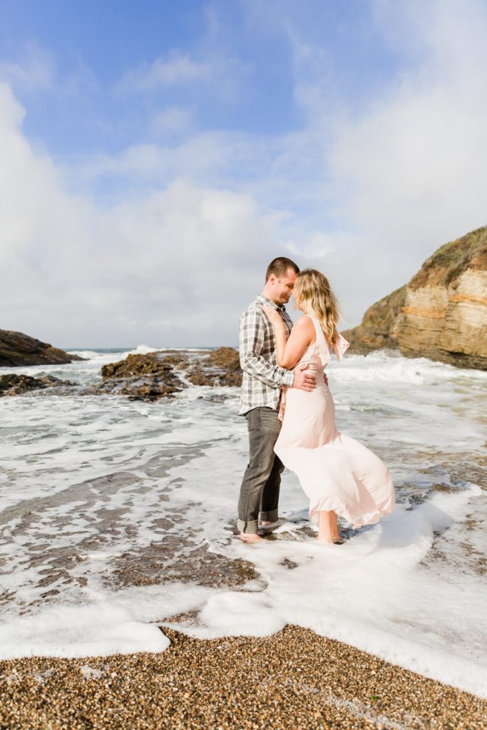 engaged couple kissing in the waters of the pacific ocean in montana de oro