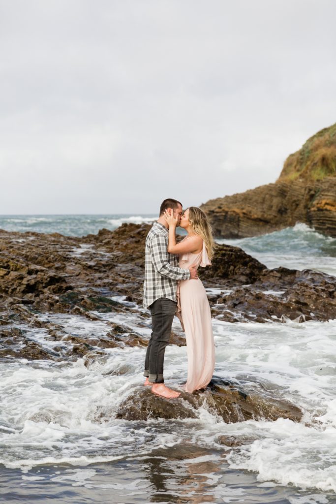 couple kissing on the rocky shores of the california coast
