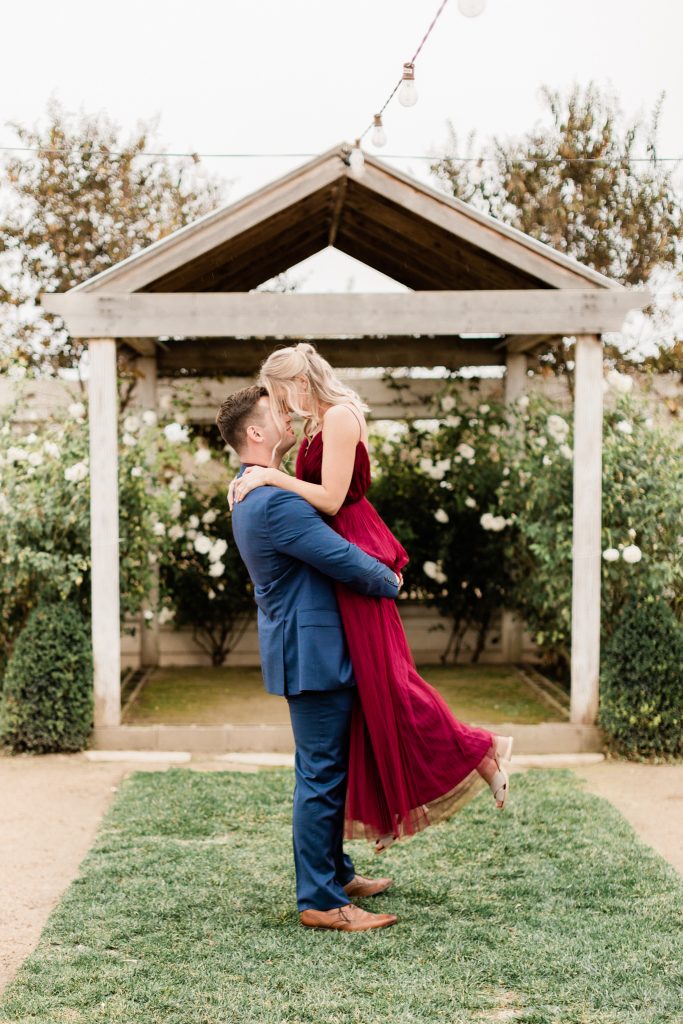 man picking up his fiance in front of a gazebo