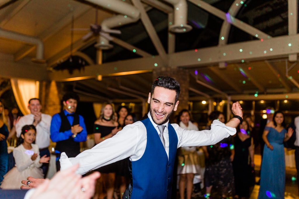 groomsman in blue vest dancing at reception