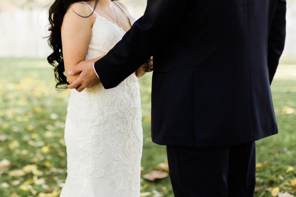 groom  holding brides arm, lace detail of wedding dress