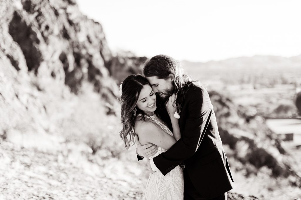 black and white couple nuzzling pose on the cliffs in the arizona desert