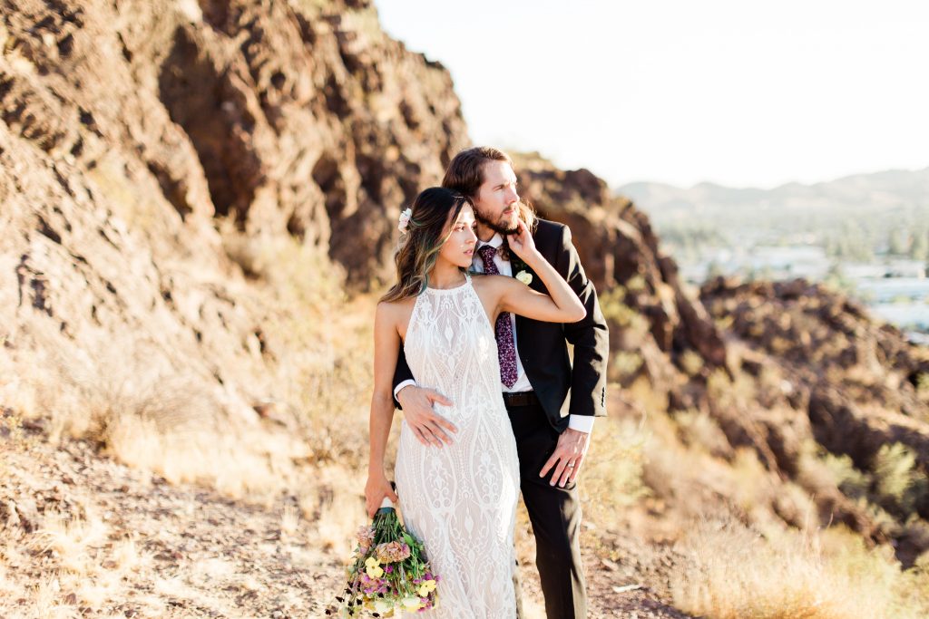 bohemian wedding couple embracing romantically while standing on the cliffs of tempe arizona at sunset