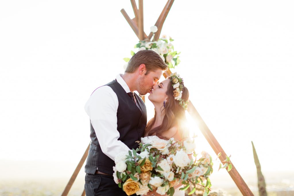 bohemian florals and a-frame with couple kissing at sunset