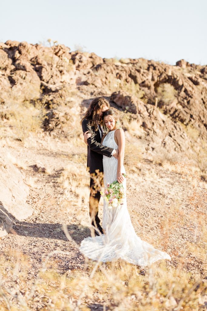 newly married couple embracing in at sunset after their desert elopement