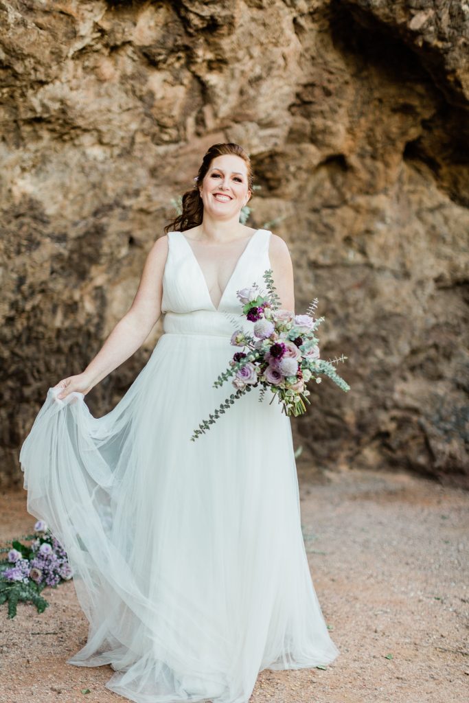bride laughing and smiling while holding a bouquet for a desert bridal session