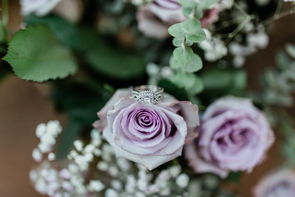 neil lane princess cut wedding ring and anniversary band sitting on top of a lavender rose
