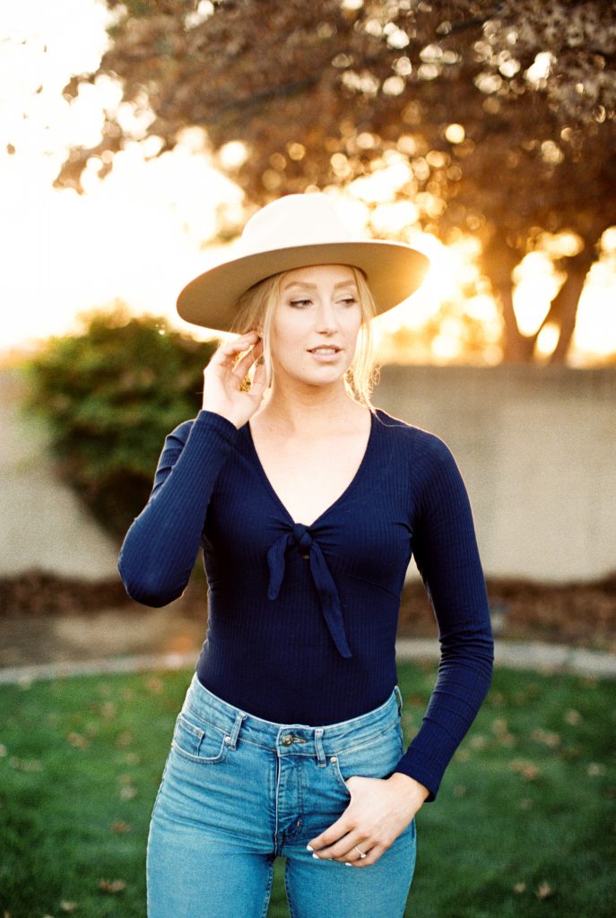 blonde woman standing in the grass with her thumb in the pocket of her jeans
