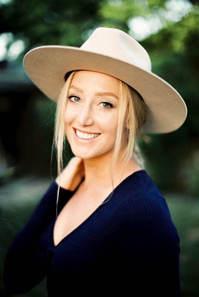 blonde woman wearing a beige suede hat and a navy blue shirt